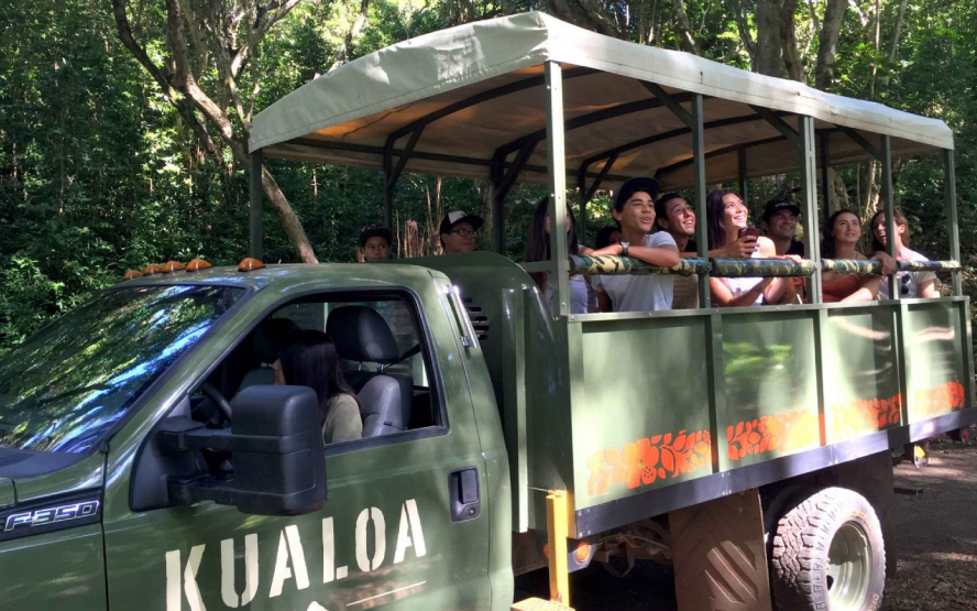 A vehicle with multiple people inside a cart looking at dinosaurs